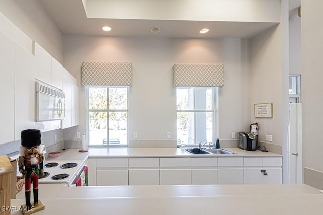 kitchen featuring white appliances, white cabinetry, and sink