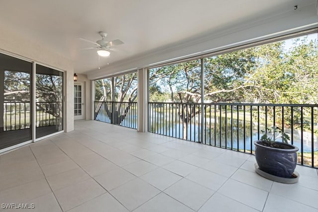 unfurnished sunroom with a water view and ceiling fan