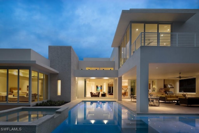 pool at dusk featuring a patio, an in ground hot tub, and outdoor lounge area