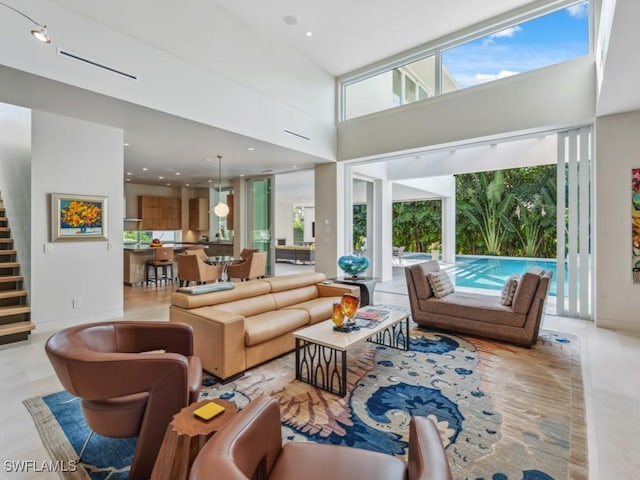 living room featuring a towering ceiling, stairs, and recessed lighting