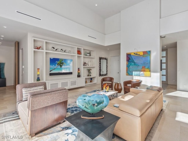 living room with a towering ceiling, built in shelves, and recessed lighting