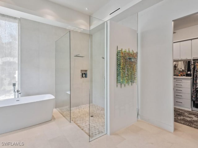 full bathroom featuring a walk in closet, a soaking tub, and a walk in shower