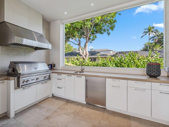 kitchen with a sink, white cabinets, light countertops, fridge, and decorative backsplash