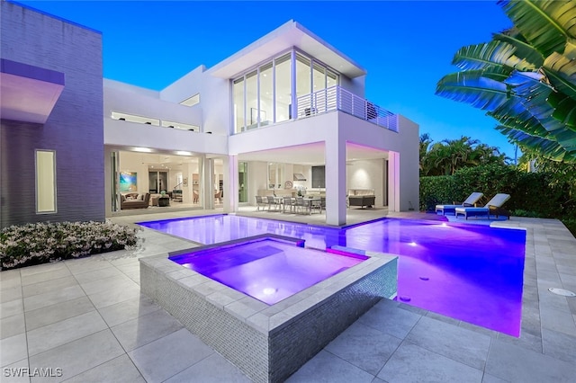 pool at dusk featuring outdoor dining space, a pool with connected hot tub, and a patio