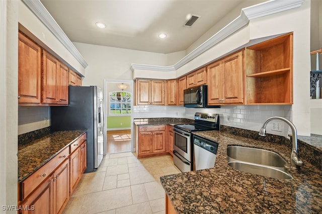 kitchen with backsplash, dark stone counters, sink, light tile patterned floors, and stainless steel appliances