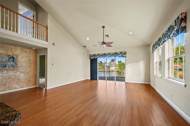 unfurnished living room featuring ceiling fan, hardwood / wood-style floors, a water view, and high vaulted ceiling