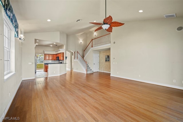 unfurnished living room featuring high vaulted ceiling, light hardwood / wood-style flooring, and ceiling fan