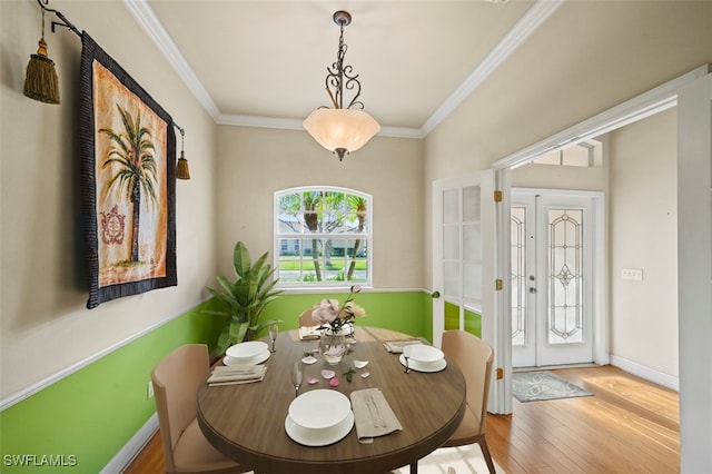 dining area with french doors, light hardwood / wood-style floors, and ornamental molding