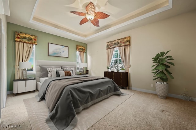 bedroom featuring a raised ceiling, ceiling fan, and light carpet