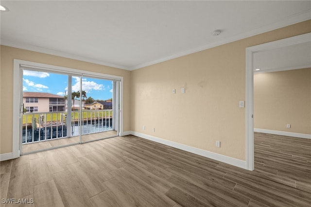 spare room with a water view, hardwood / wood-style flooring, and ornamental molding