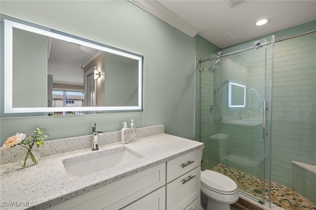 bathroom with toilet, vanity, an enclosed shower, and ornamental molding