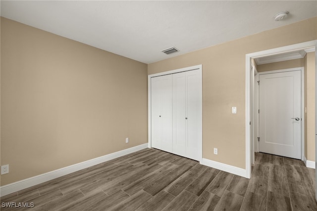 unfurnished bedroom featuring a closet and dark wood-type flooring