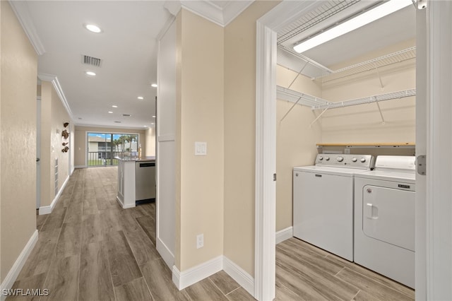 laundry area featuring washing machine and clothes dryer, light hardwood / wood-style floors, and ornamental molding