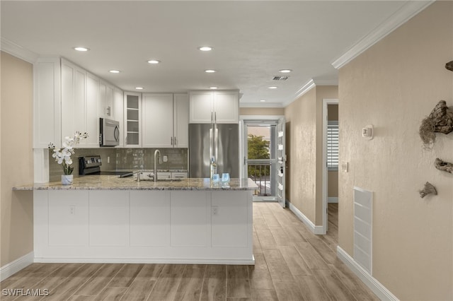 kitchen with light stone counters, kitchen peninsula, sink, and appliances with stainless steel finishes