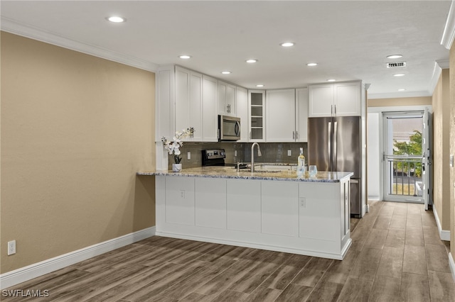 kitchen with white cabinets, sink, light stone counters, kitchen peninsula, and stainless steel appliances