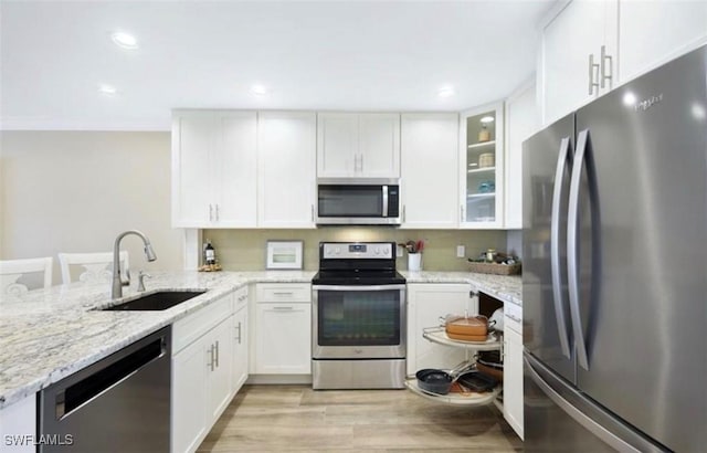 kitchen featuring sink, light stone countertops, light wood-type flooring, white cabinetry, and stainless steel appliances