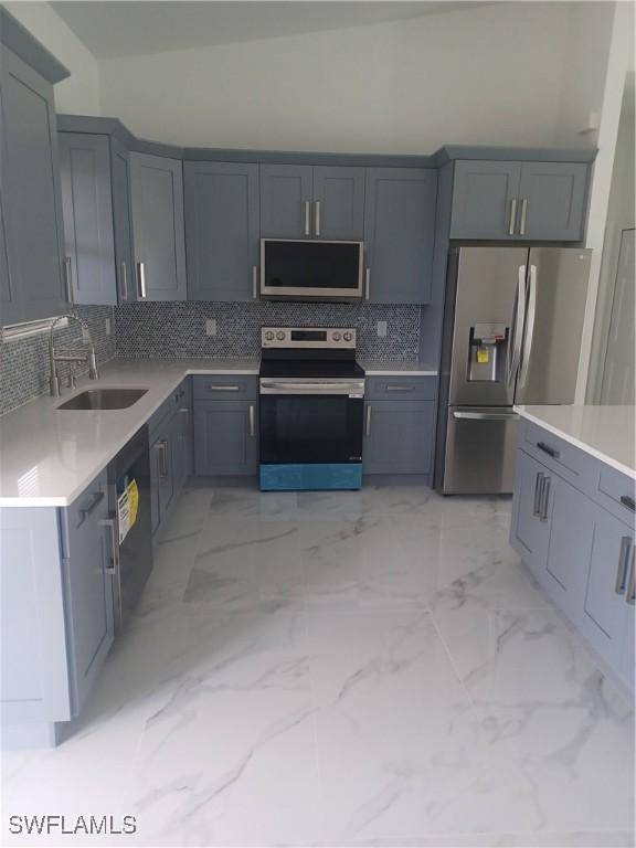 kitchen with appliances with stainless steel finishes, tasteful backsplash, gray cabinets, and sink