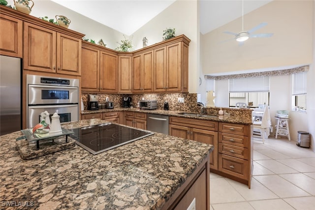 kitchen with high vaulted ceiling, light tile patterned floors, appliances with stainless steel finishes, kitchen peninsula, and decorative backsplash