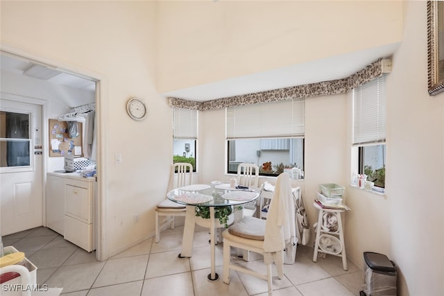 tiled dining space with washer / dryer, plenty of natural light, and a high ceiling