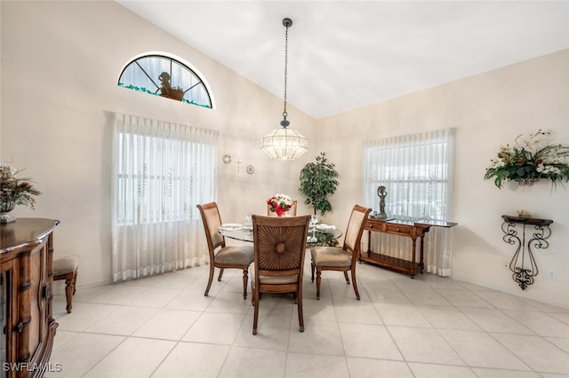 dining room with vaulted ceiling, plenty of natural light, light tile patterned floors, and an inviting chandelier