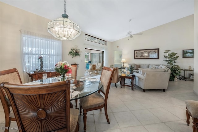 tiled dining space with ceiling fan with notable chandelier and high vaulted ceiling