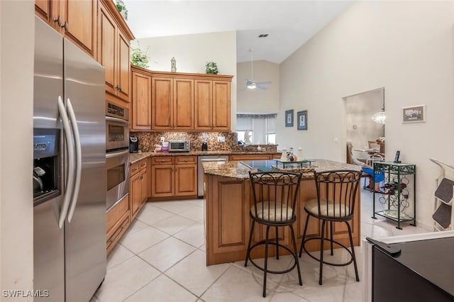 kitchen featuring a kitchen island, appliances with stainless steel finishes, decorative light fixtures, tasteful backsplash, and light stone counters