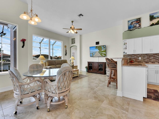 dining space featuring ceiling fan with notable chandelier and sink