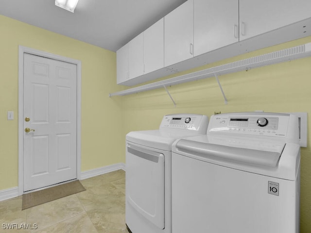 clothes washing area featuring washer and dryer and cabinets