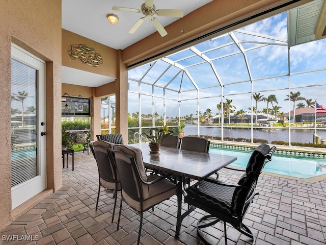 view of patio / terrace featuring glass enclosure, ceiling fan, and a water view