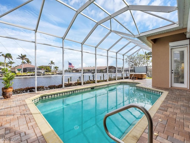 view of pool with a jacuzzi, a patio, a water view, and a lanai