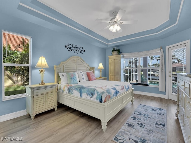 bedroom featuring hardwood / wood-style flooring, ceiling fan, and a raised ceiling