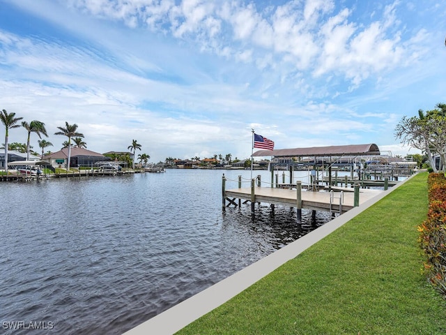 view of dock featuring a lawn and a water view