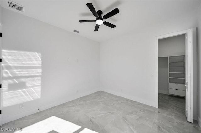 unfurnished bedroom with ceiling fan, a walk in closet, and a closet