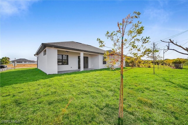 rear view of property with a lawn and ceiling fan