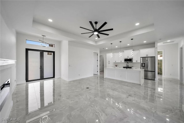 unfurnished living room featuring french doors, a tray ceiling, ceiling fan, and sink