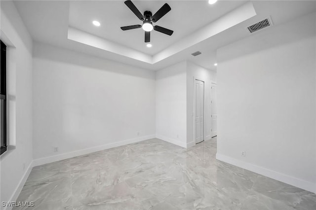 empty room featuring a raised ceiling and ceiling fan