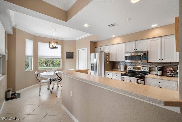 kitchen with hanging light fixtures, stainless steel appliances, light tile patterned floors, backsplash, and white cabinets