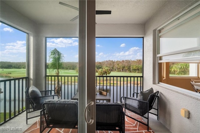 sunroom / solarium featuring a water view and ceiling fan