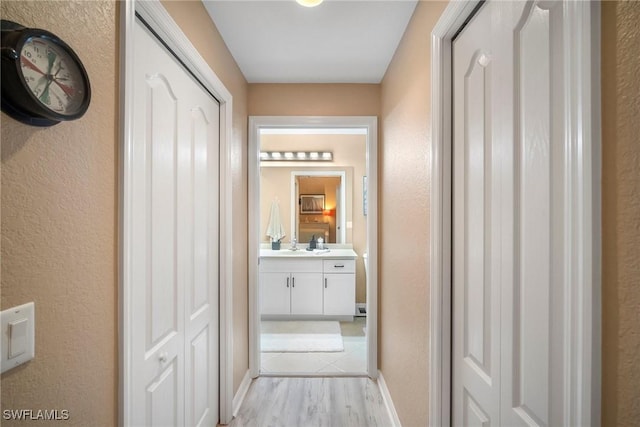 corridor with light hardwood / wood-style flooring and sink