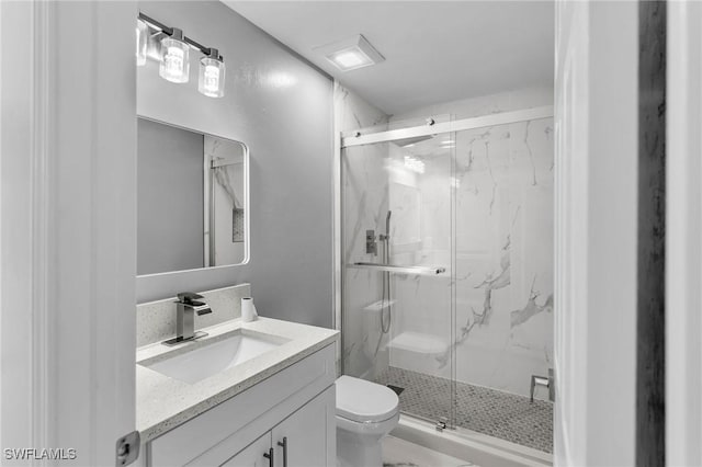 bathroom featuring vanity, toilet, and a shower with shower door