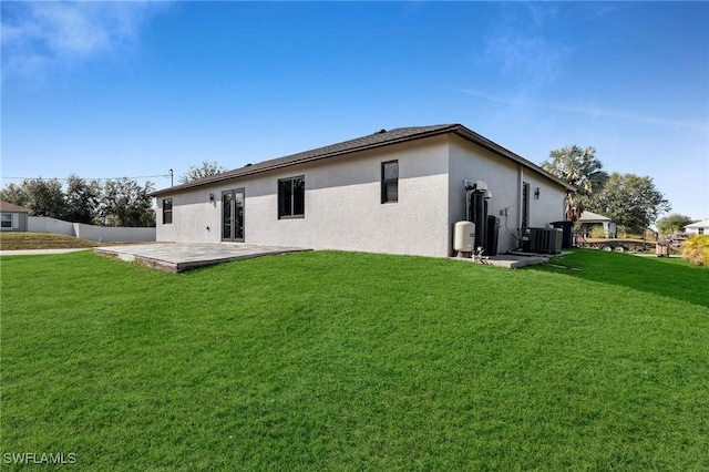 rear view of property with central AC unit, a patio area, and a yard