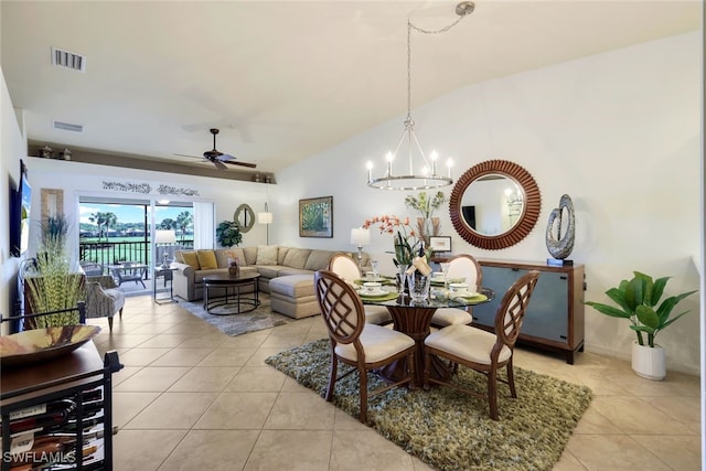 dining room with ceiling fan with notable chandelier, light tile patterned floors, and vaulted ceiling