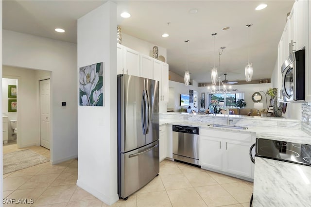 kitchen featuring kitchen peninsula, light stone counters, stainless steel appliances, sink, and white cabinets