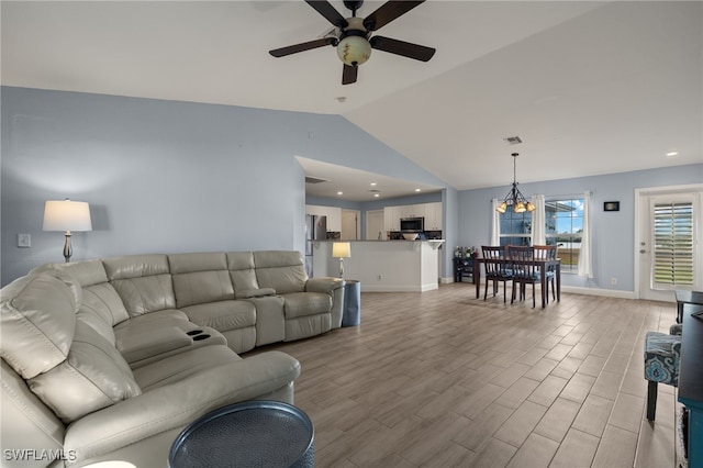 living room with lofted ceiling and ceiling fan with notable chandelier