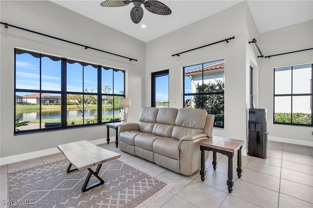 living room with ceiling fan, light tile patterned floors, and a water view