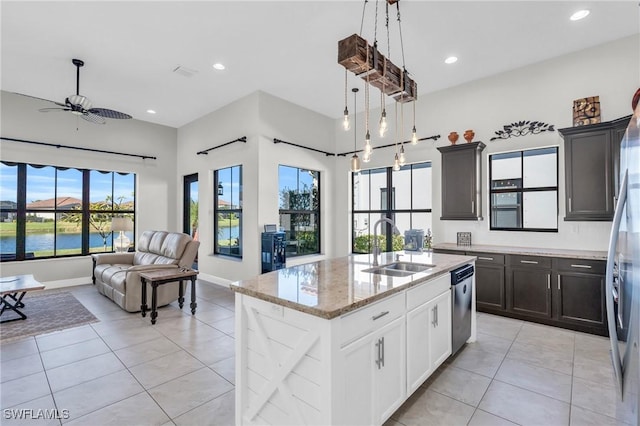 kitchen featuring sink, appliances with stainless steel finishes, an island with sink, a water view, and white cabinets