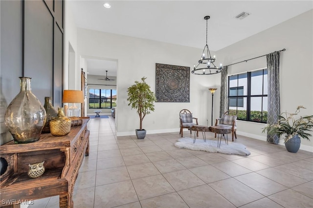 dining space featuring light tile patterned floors, a healthy amount of sunlight, and ceiling fan with notable chandelier