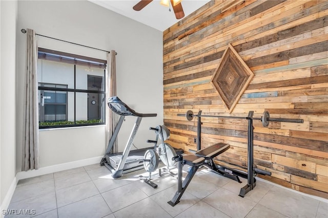 workout area featuring ceiling fan, light tile patterned floors, and wooden walls