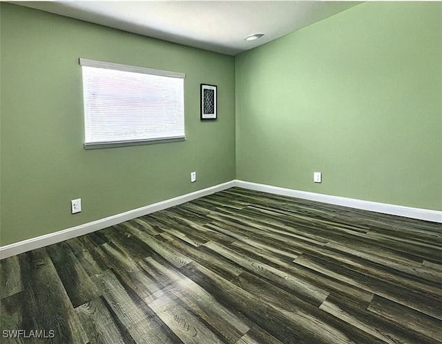 empty room with dark wood-style flooring and baseboards