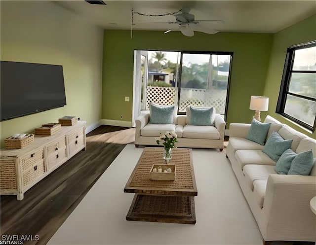 living room featuring dark wood-style flooring, a ceiling fan, and baseboards